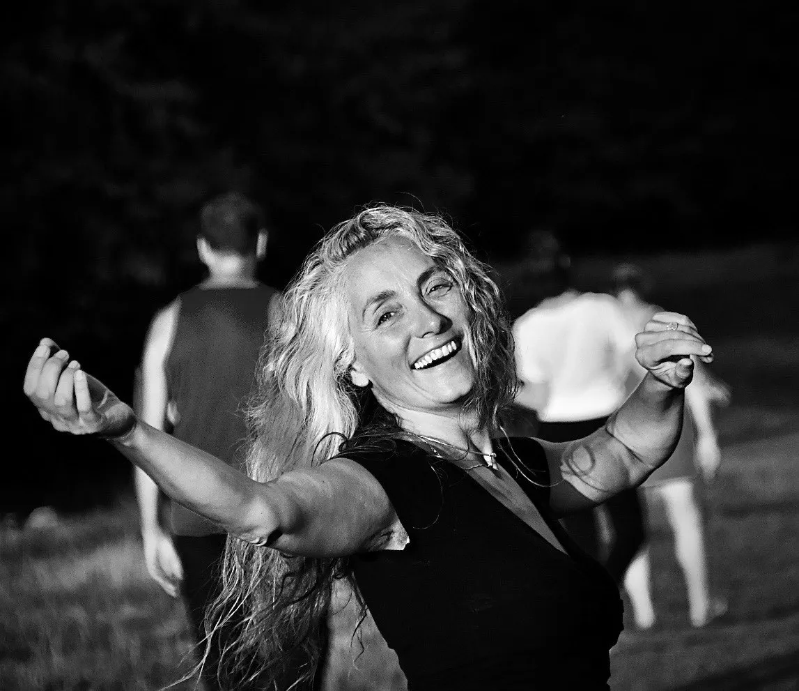 Julia Knežević in Bewegung, lachend und offen im Kreis tanzender Menschen.